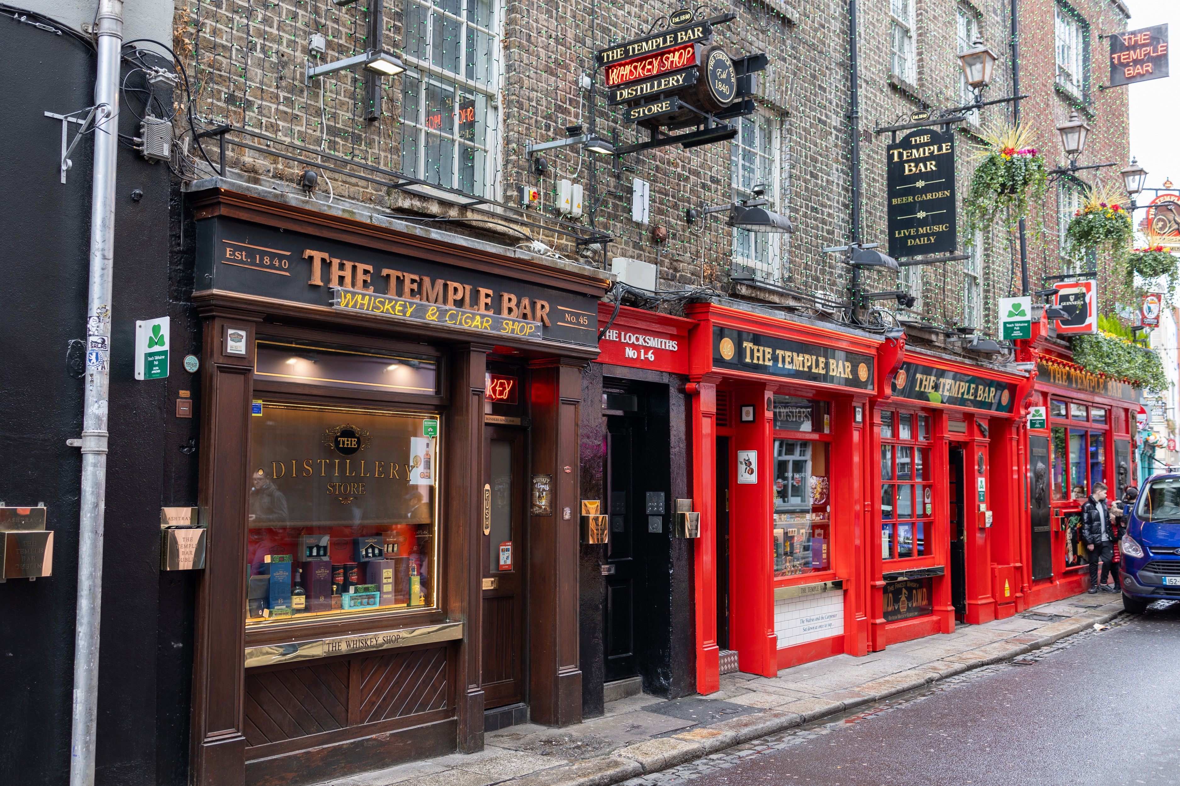 Colorful storefronts and pubs on a pedestrian street in a historic city.