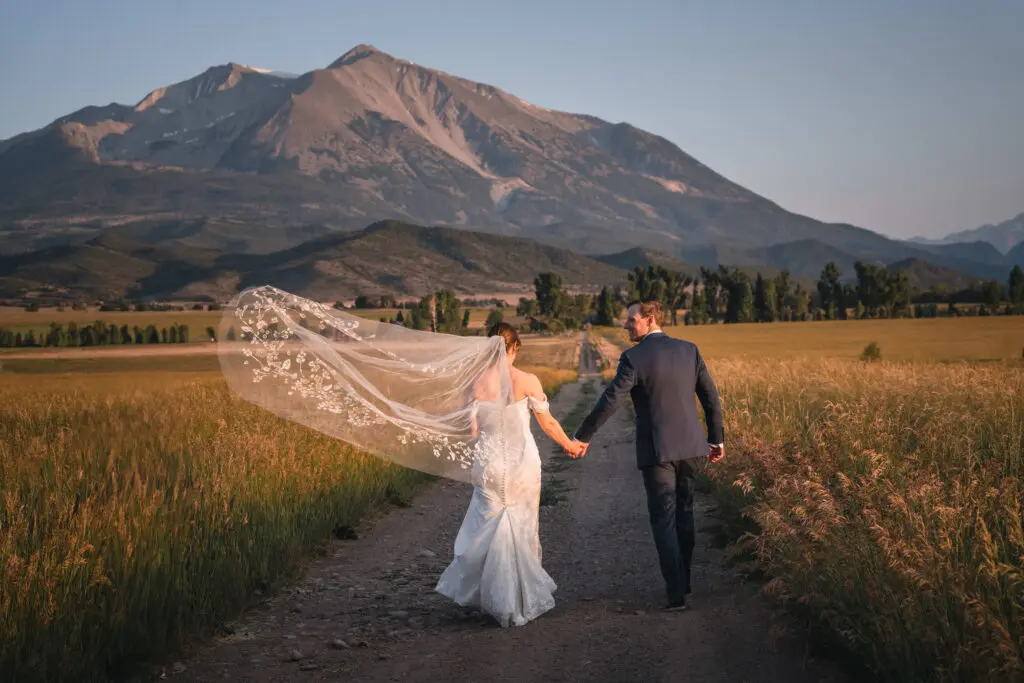 Couple walking through golden field during Carbondale Private Ranch Wedding