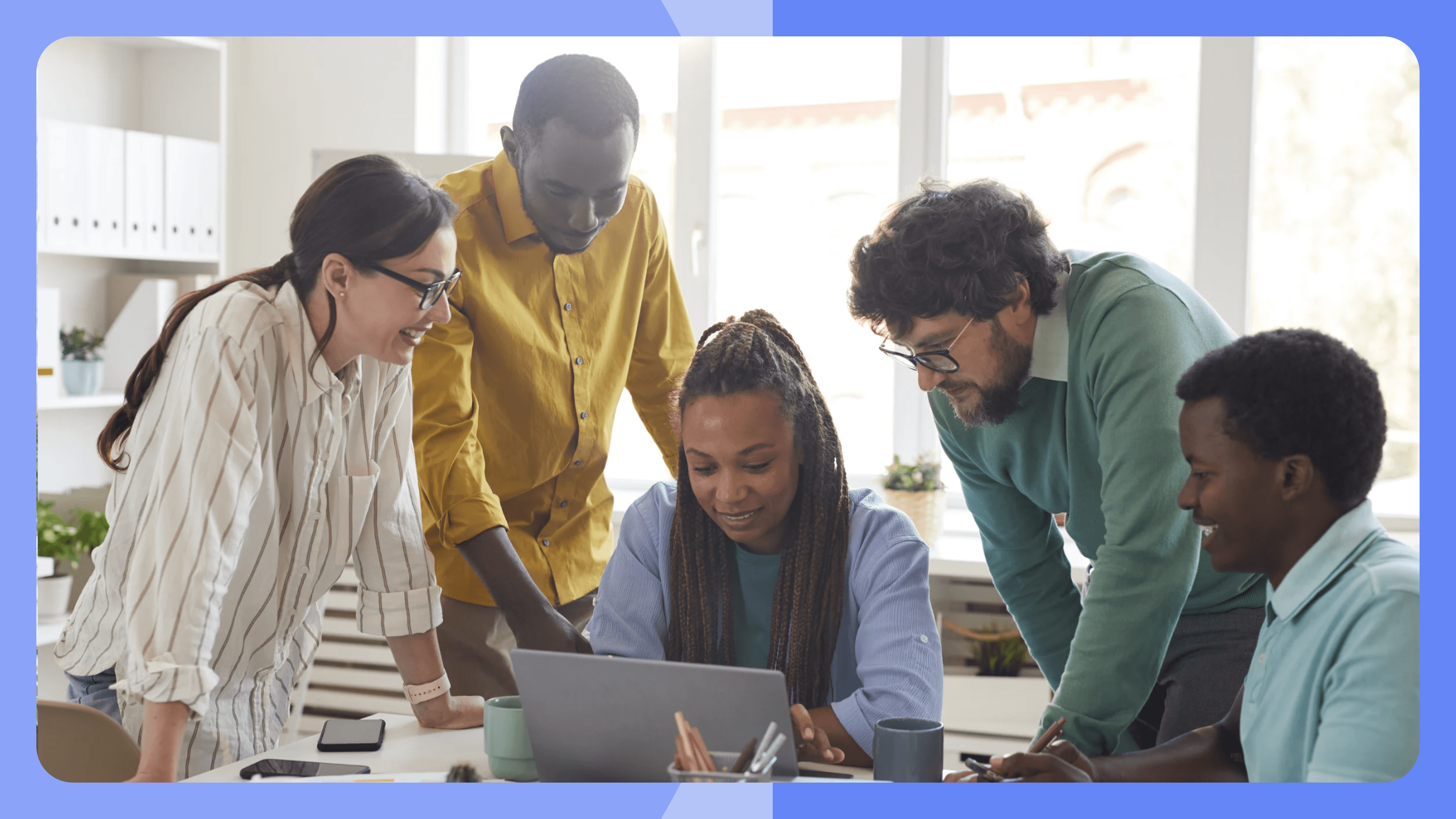 Gruppe an Personen die gemeinsam auf einen Laptop schauen.