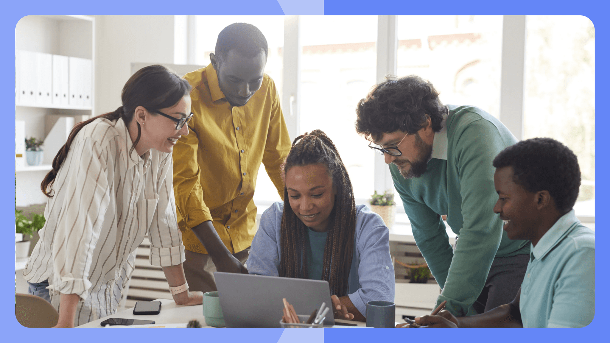 Gruppe an Personen die gemeinsam auf einen Laptop schauen.