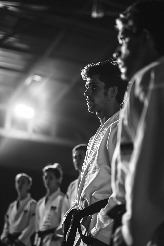 Instructor in a white gi with a red belt standing confidently with arms crossed