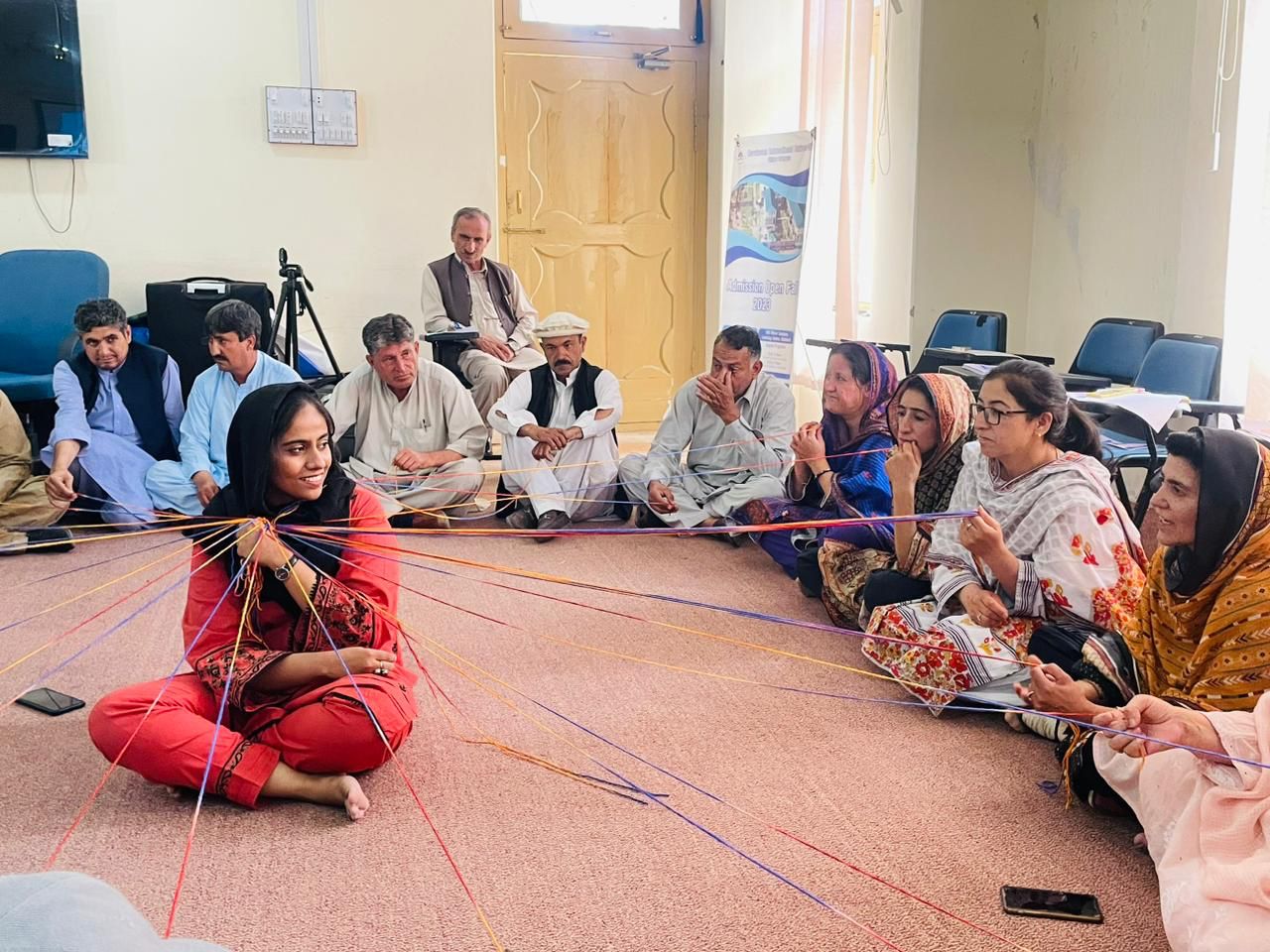 Rutaba Syed of CFAW conducting a Yarn Circle Activity, where participants sit in a circle while yarn strings connect them to a central facilitator.