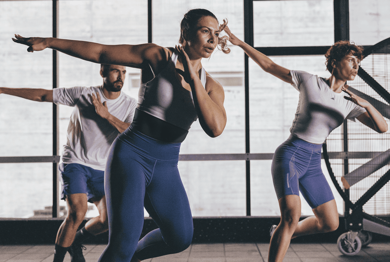 Mehrere Personen sind in der Mitte einer energetischen Bewegung während eines Bodyattack-Workouts.