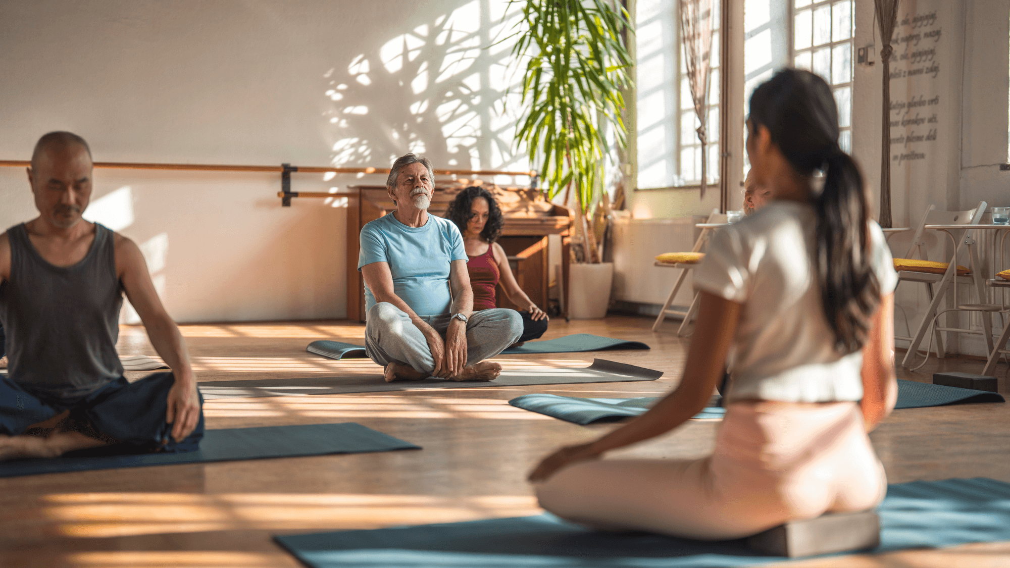 New yoga teacher sitting in a bright studio guiding a yoga class