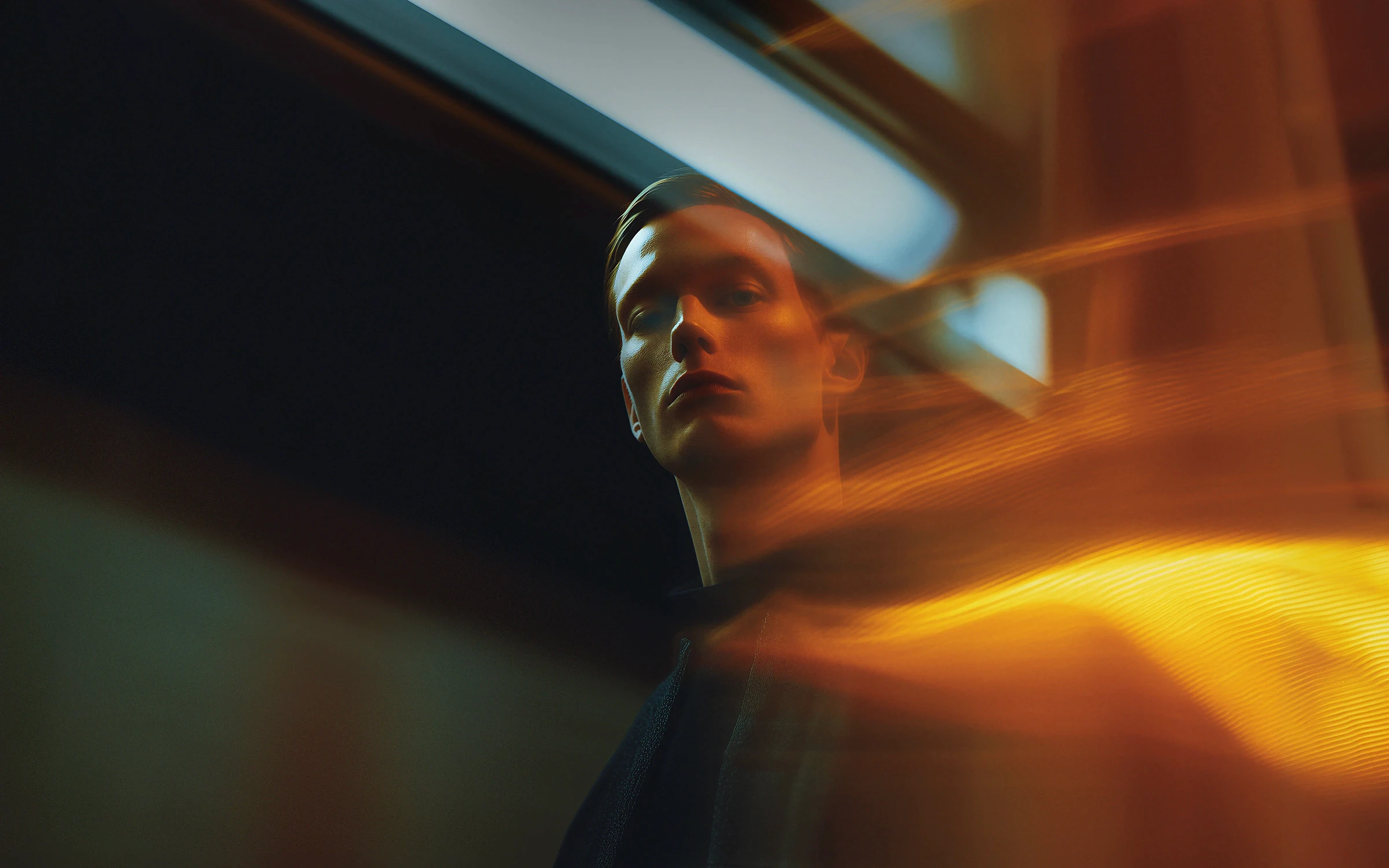 A dramatic portrait of a male model with warm lighting and dynamic light streaks.