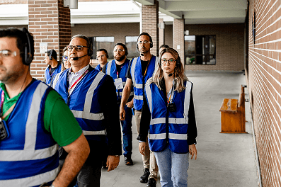 pessoas com colete azul sinalizados andando em uma fábrica