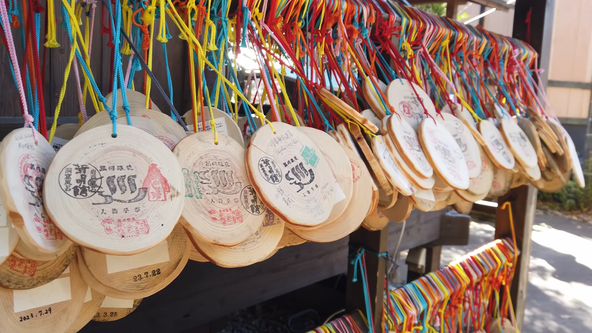Rows of wooden Kurokawa tegata bath passes hanging on coloured cords