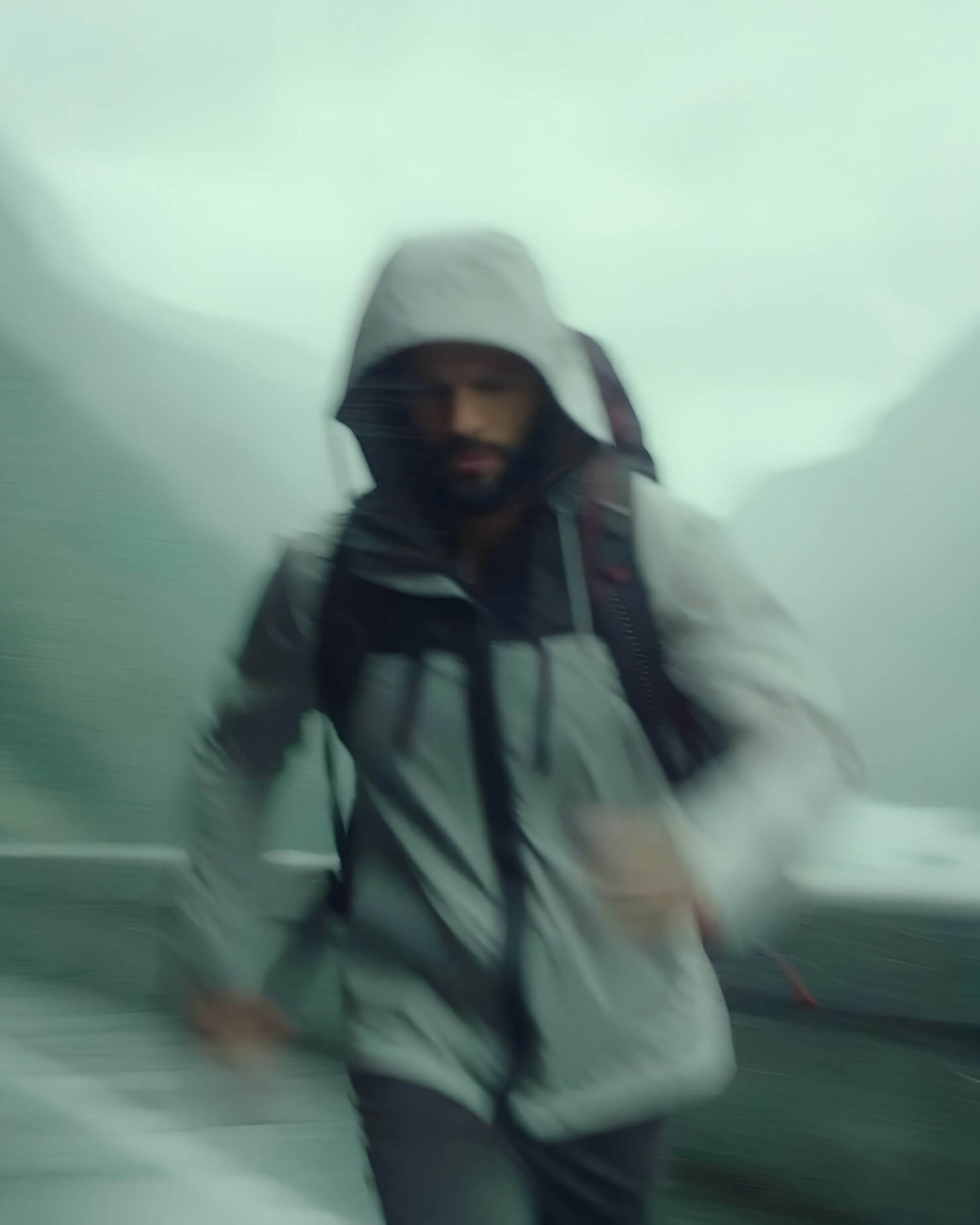 Man running outdoors in a hooded jacket with motion blur