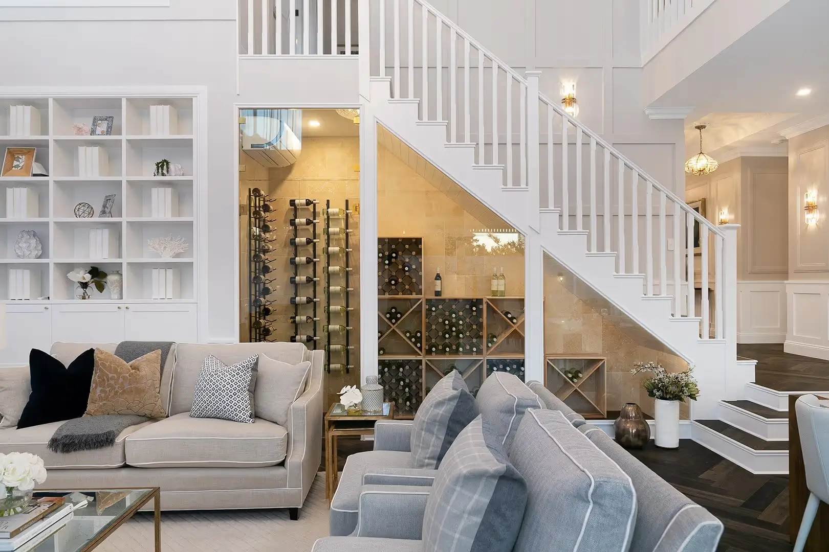 A custom wine cellar tucked beneath the stairwell framed with clear glass