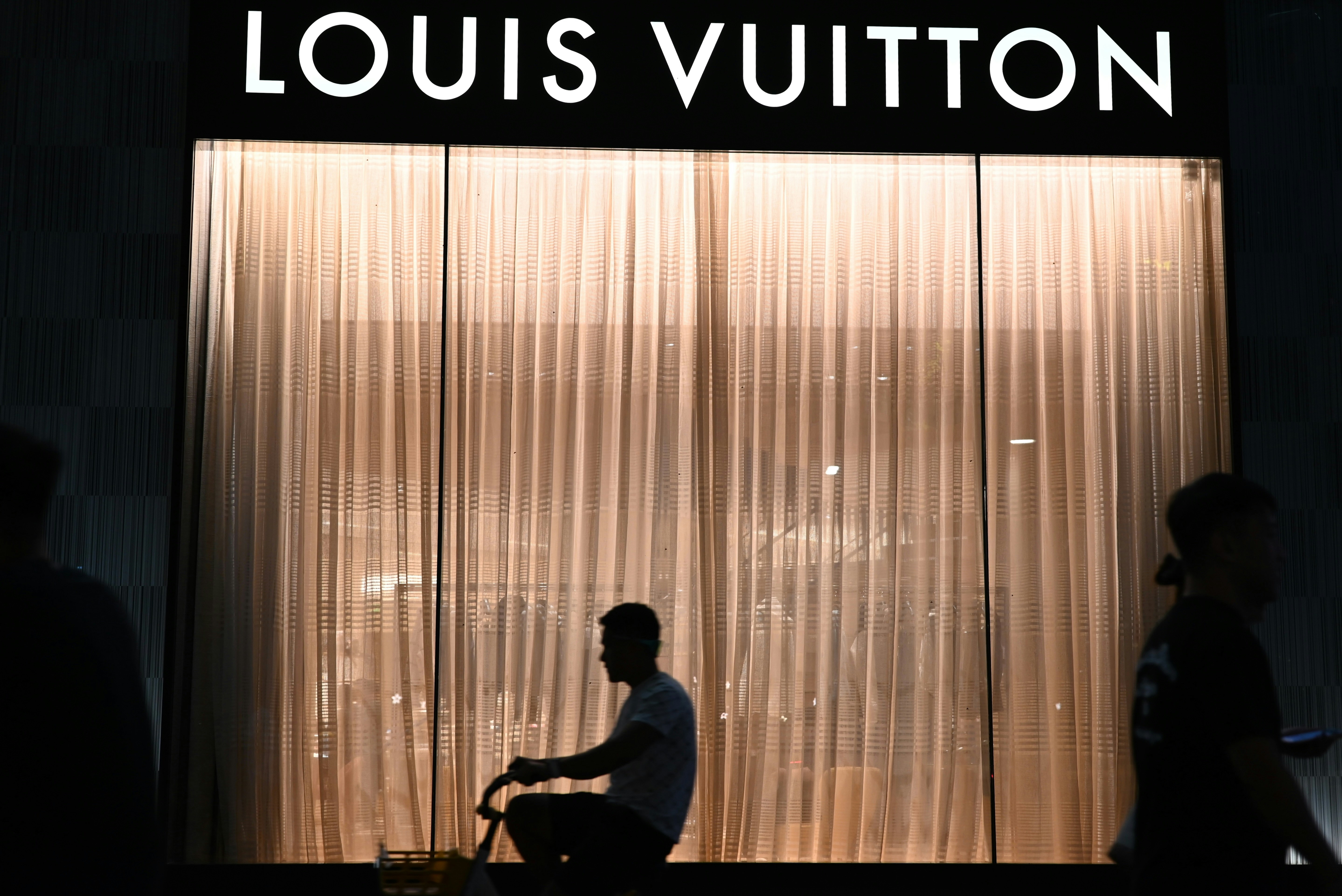 Louis vuitton store at night with people walking