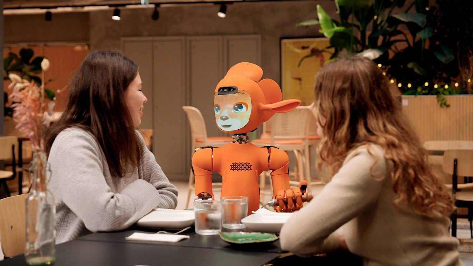 Guests interacting with a hospitality service robot at a table