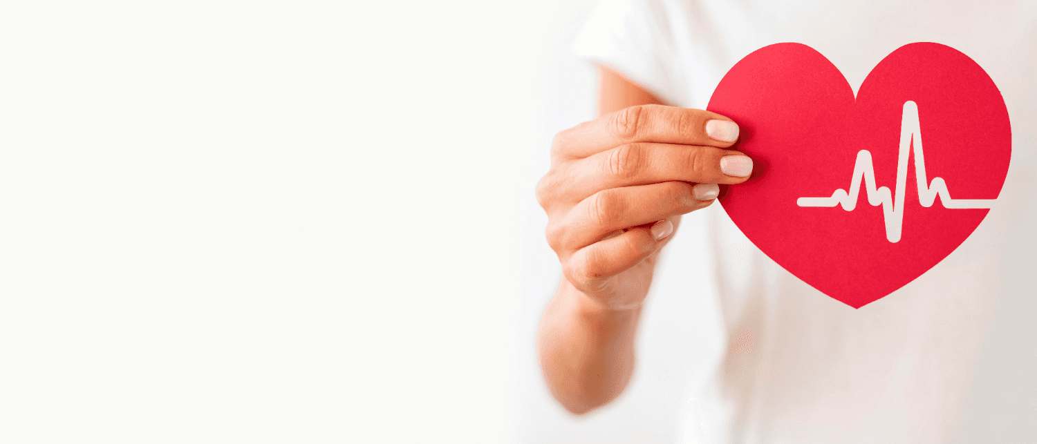 Person holding a heart-shaped cutout with ECG line