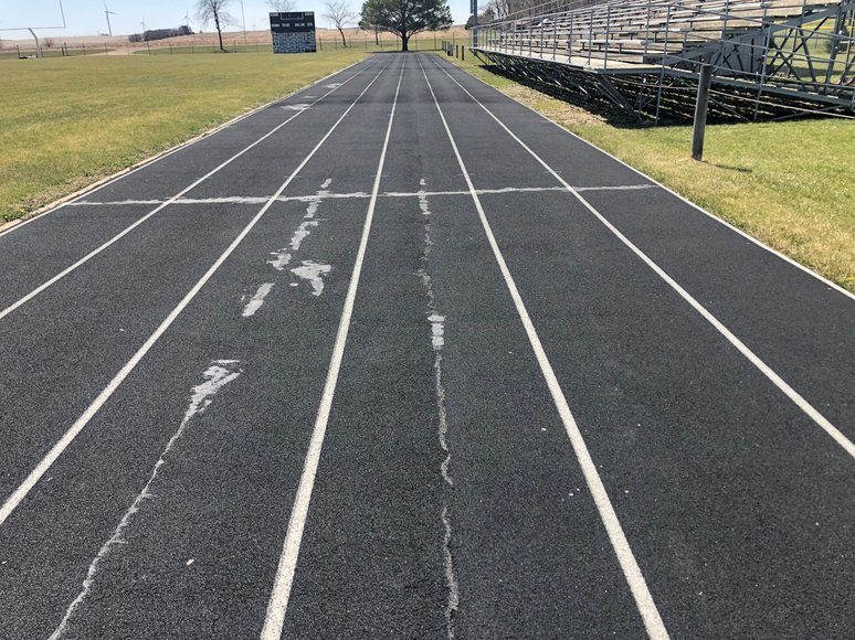 Running track cracks forming along lane lines, showing early track surface issues often caused by drainage problems.