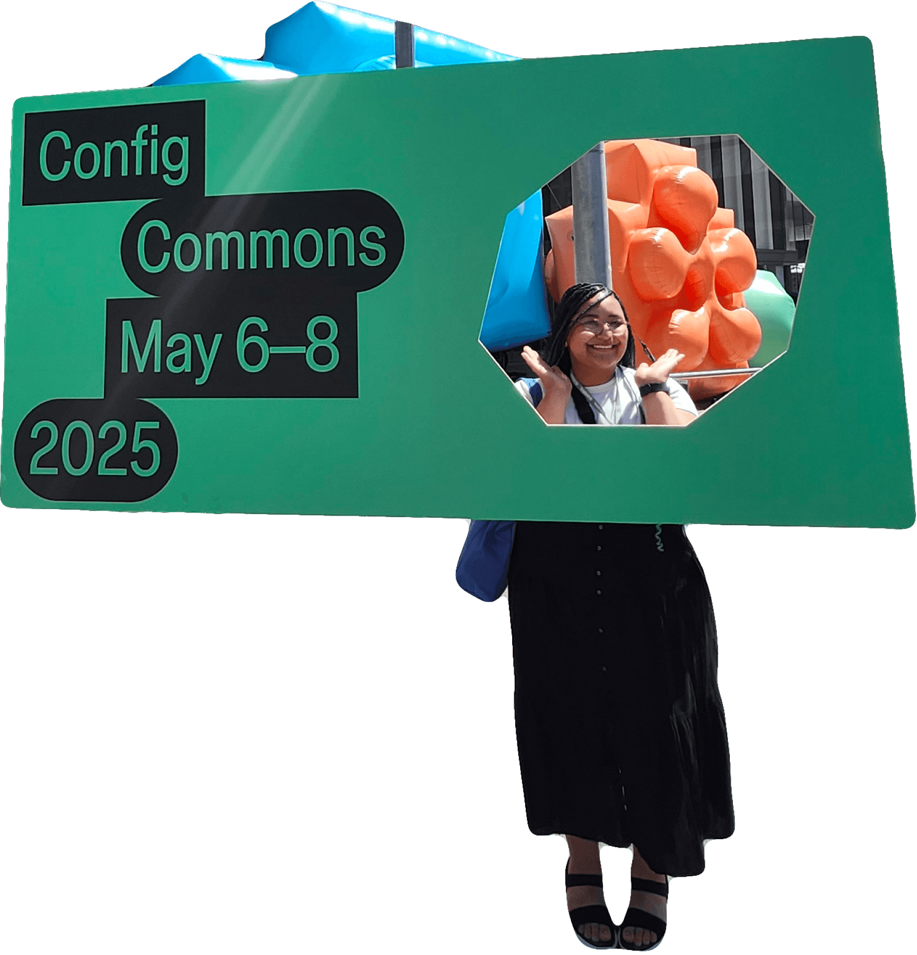 Malaika joyfully poses behind a large green cutout sign promoting "Config Commons" scheduled for May 6-8, 2025, with colorful, abstract shapes in the background.