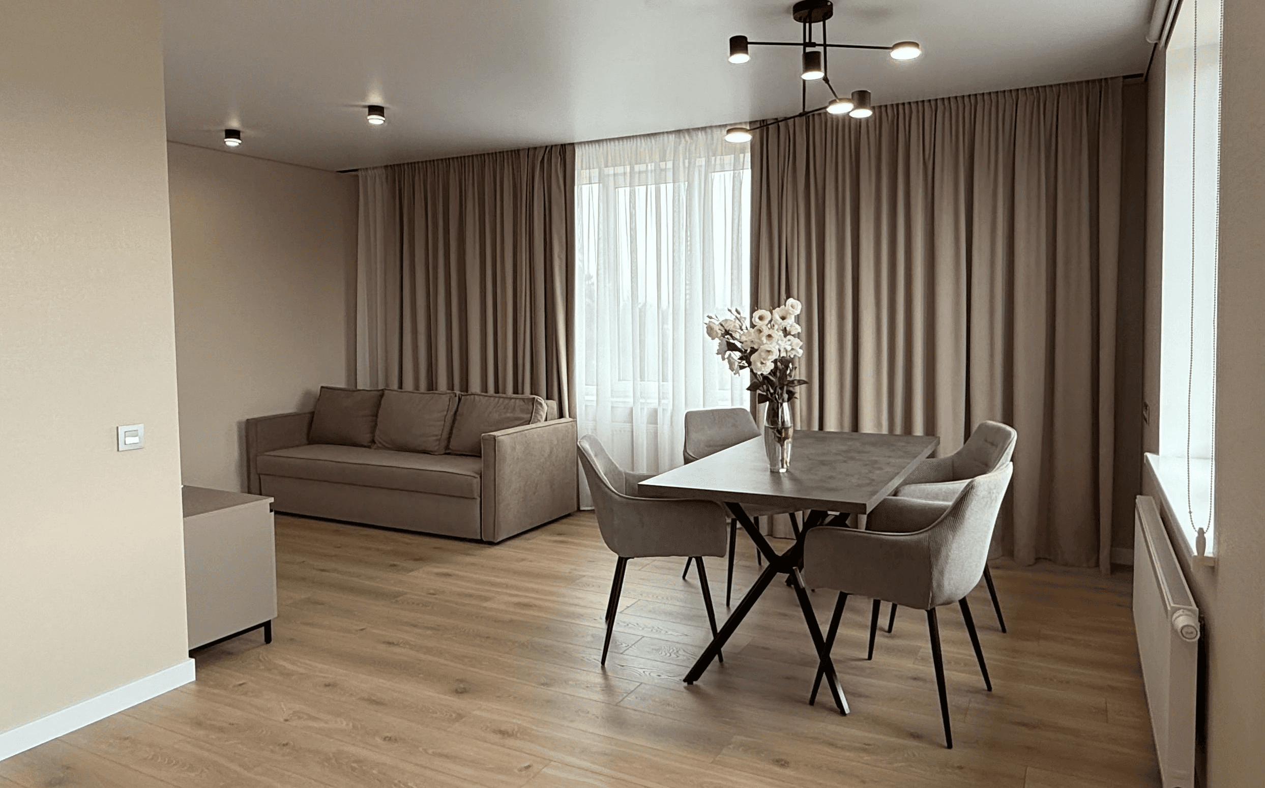 Вітальня з диваном, обіднім столом і великим вікном з фіранками