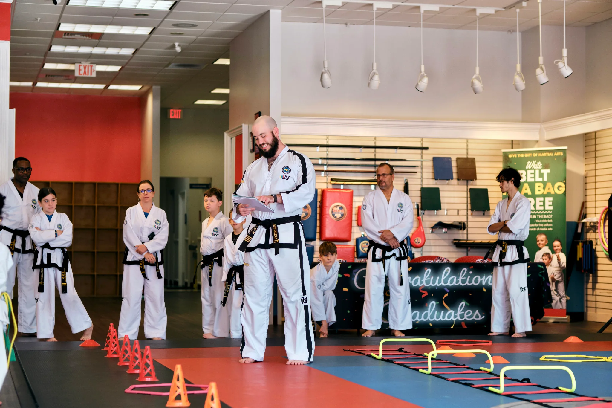 Instructor Joseph teaching with his blackbelt students standing behind him.