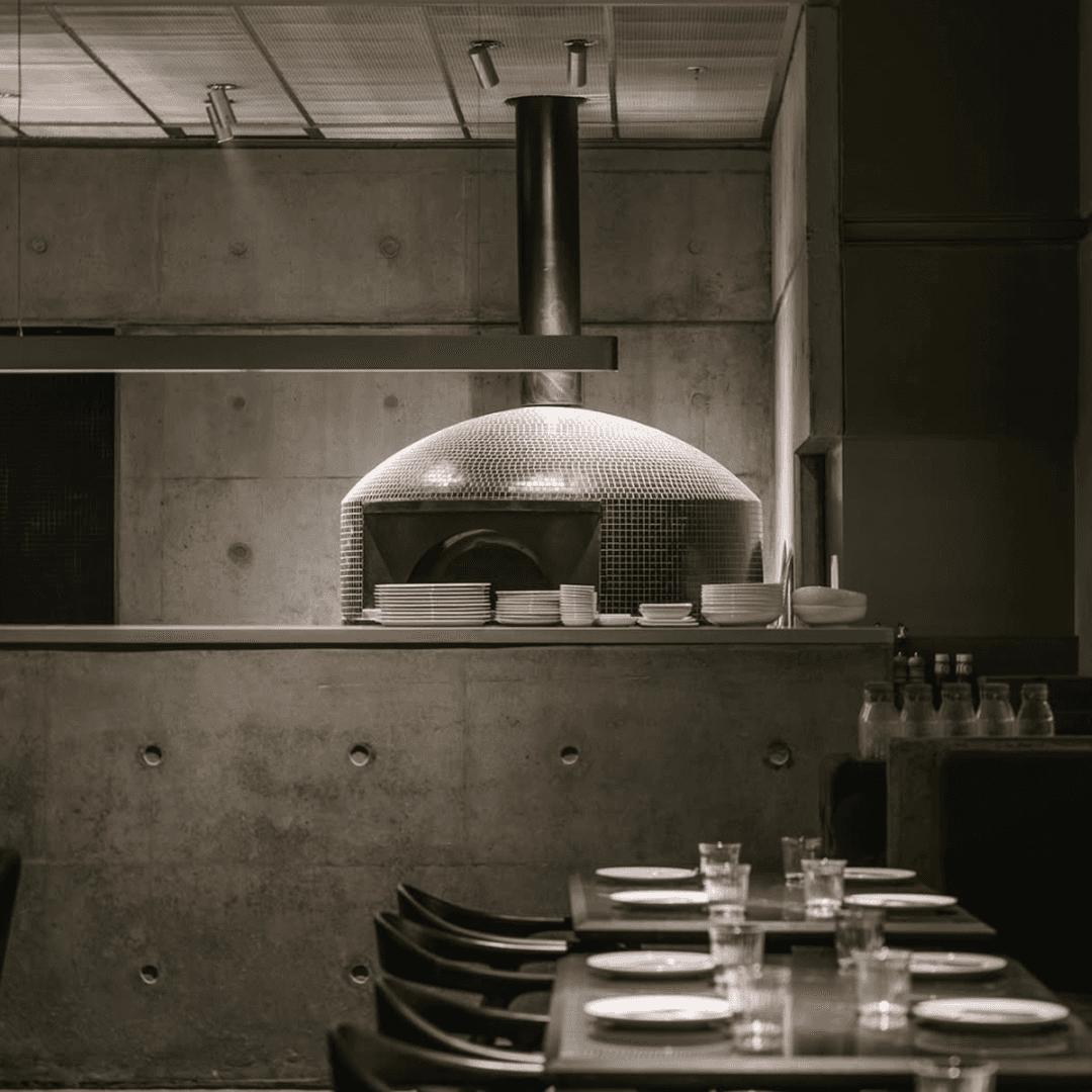 Concrete-tiled kitchen space with custom-built wood-fired oven