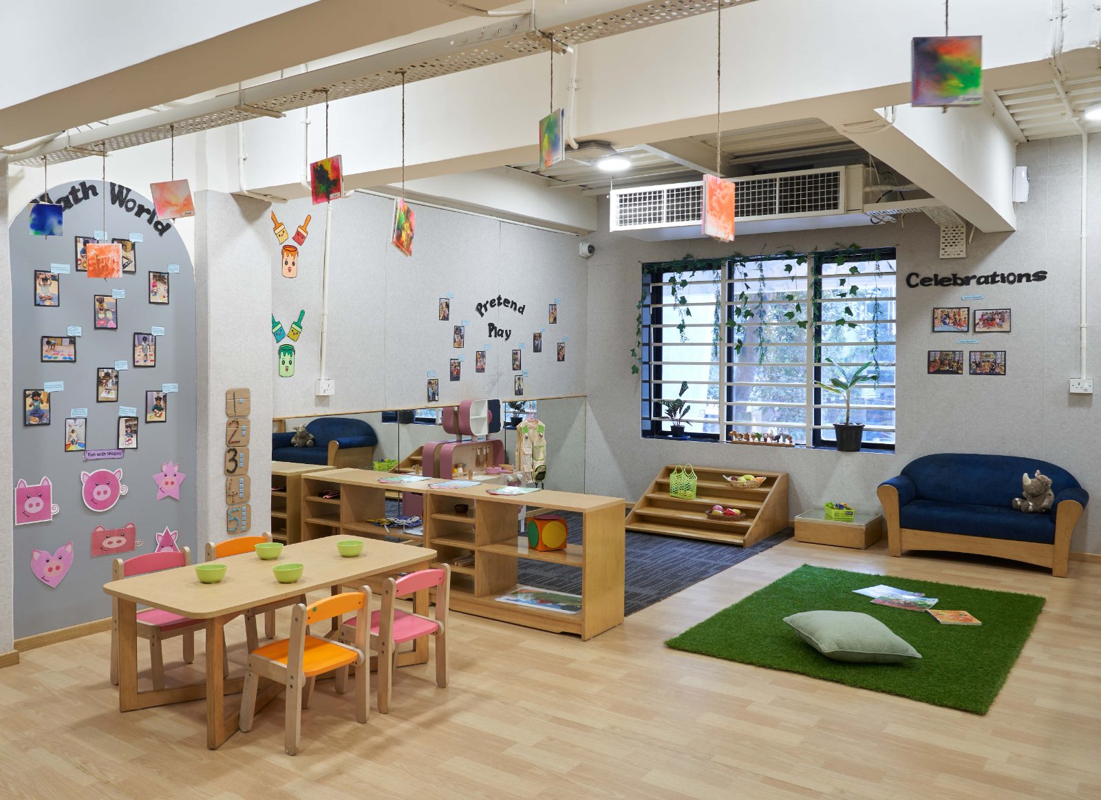 Nature-inspired preschool entrance with sculptural tree partitions and suspended green leaf ceiling panels.