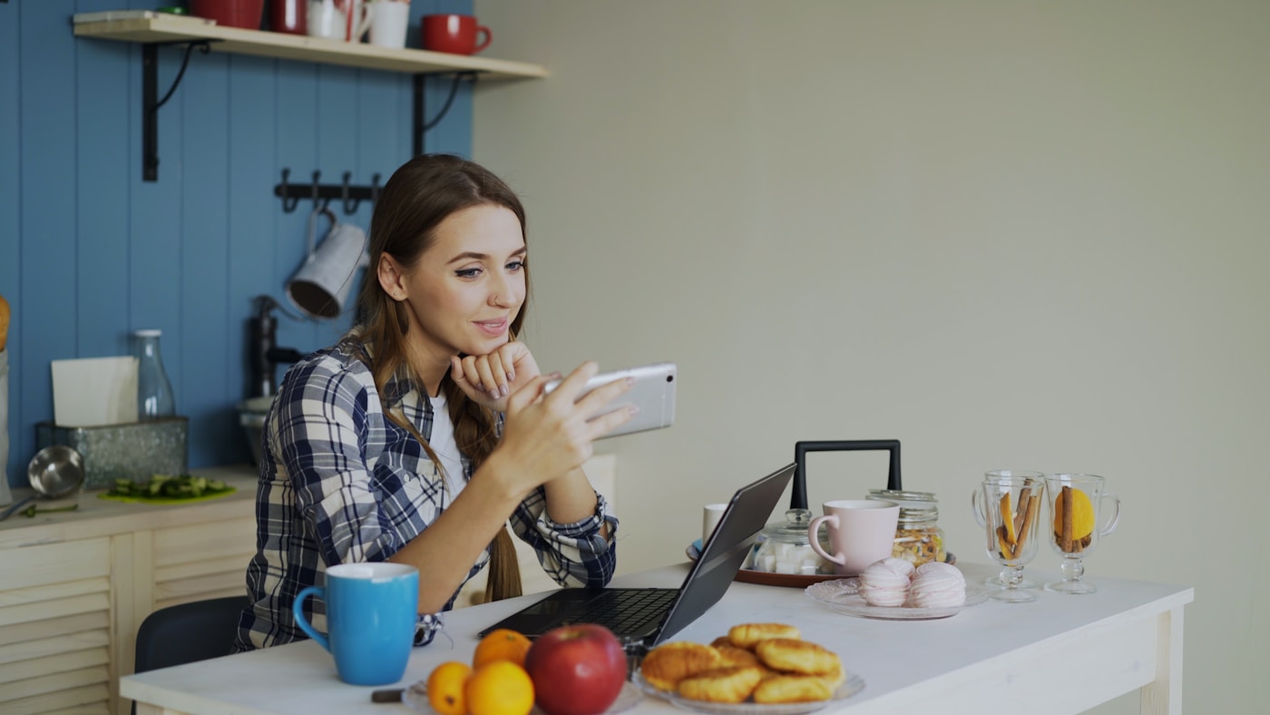 A woman on a video call at her kitchen table with fresh fruit nearby, representing the virtual nutrition support a registered dietitian provides on a GLP-1 journey.