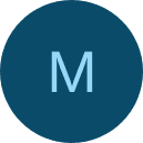 Young man with glasses in a gray hoodie, sitting in front of a computer screen with an orange background.