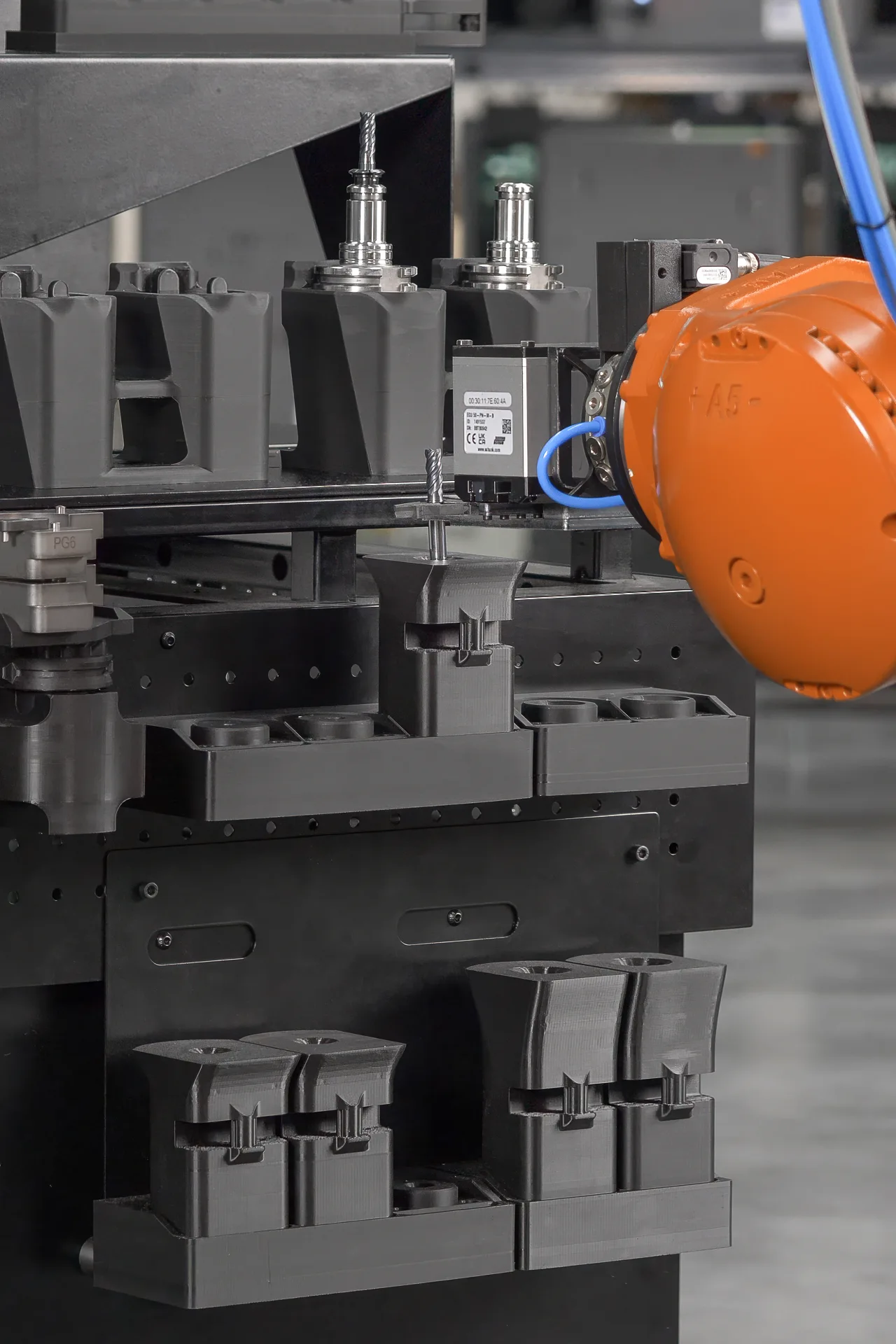 A robotic arm is precisely inserting a cutting tool into a guiding funnel to ensure accurate alignment with the receiving collet. This enables reliable tool assembly automation