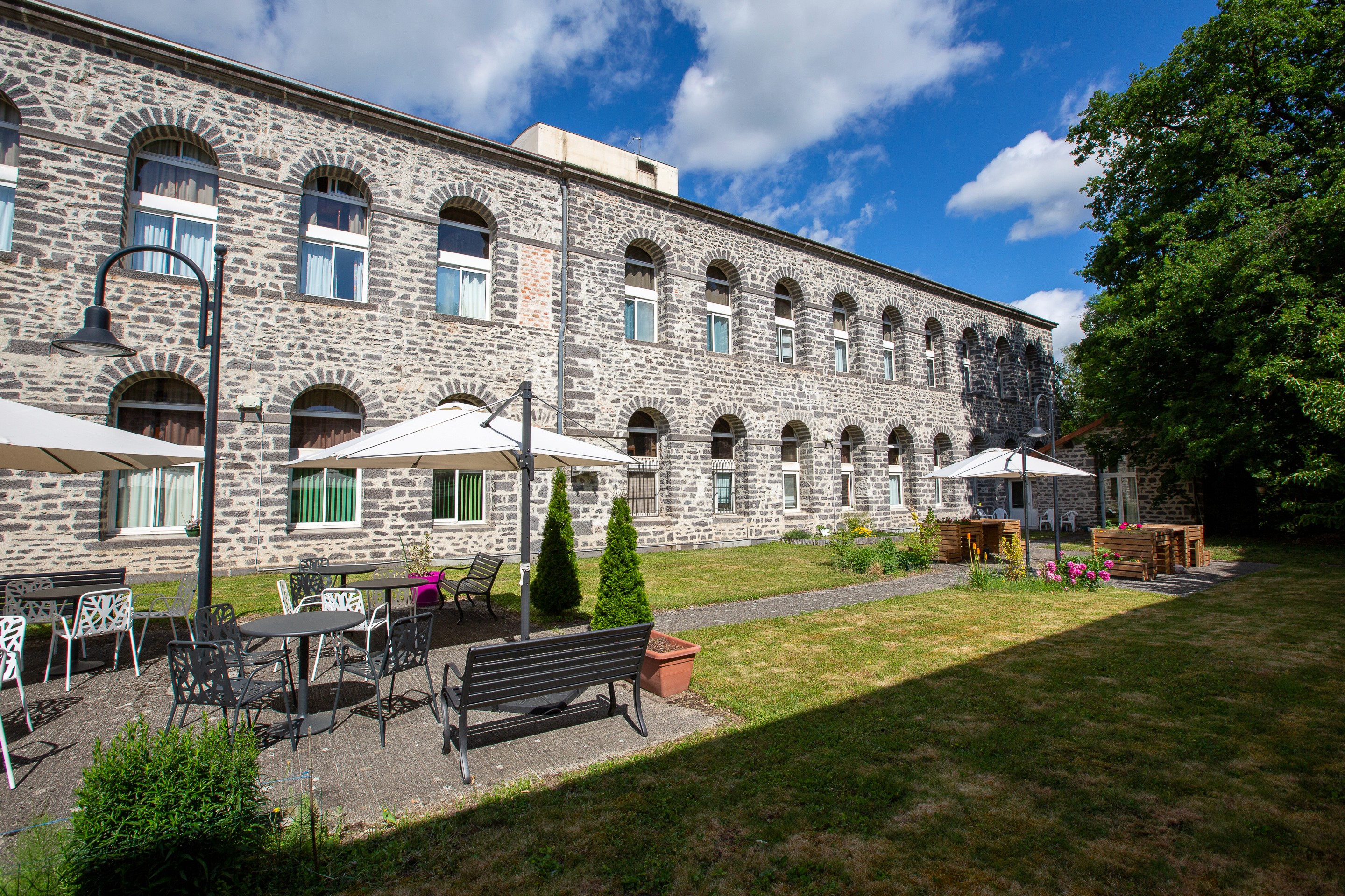 Classical residential building exterior with landscaped gardens, green lawn, and clear sky