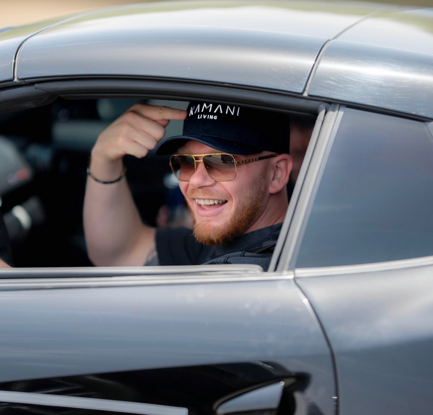 Color photo of a guitarist in a beanie playing in a rehearsal space, with bandmates blurred in the background.