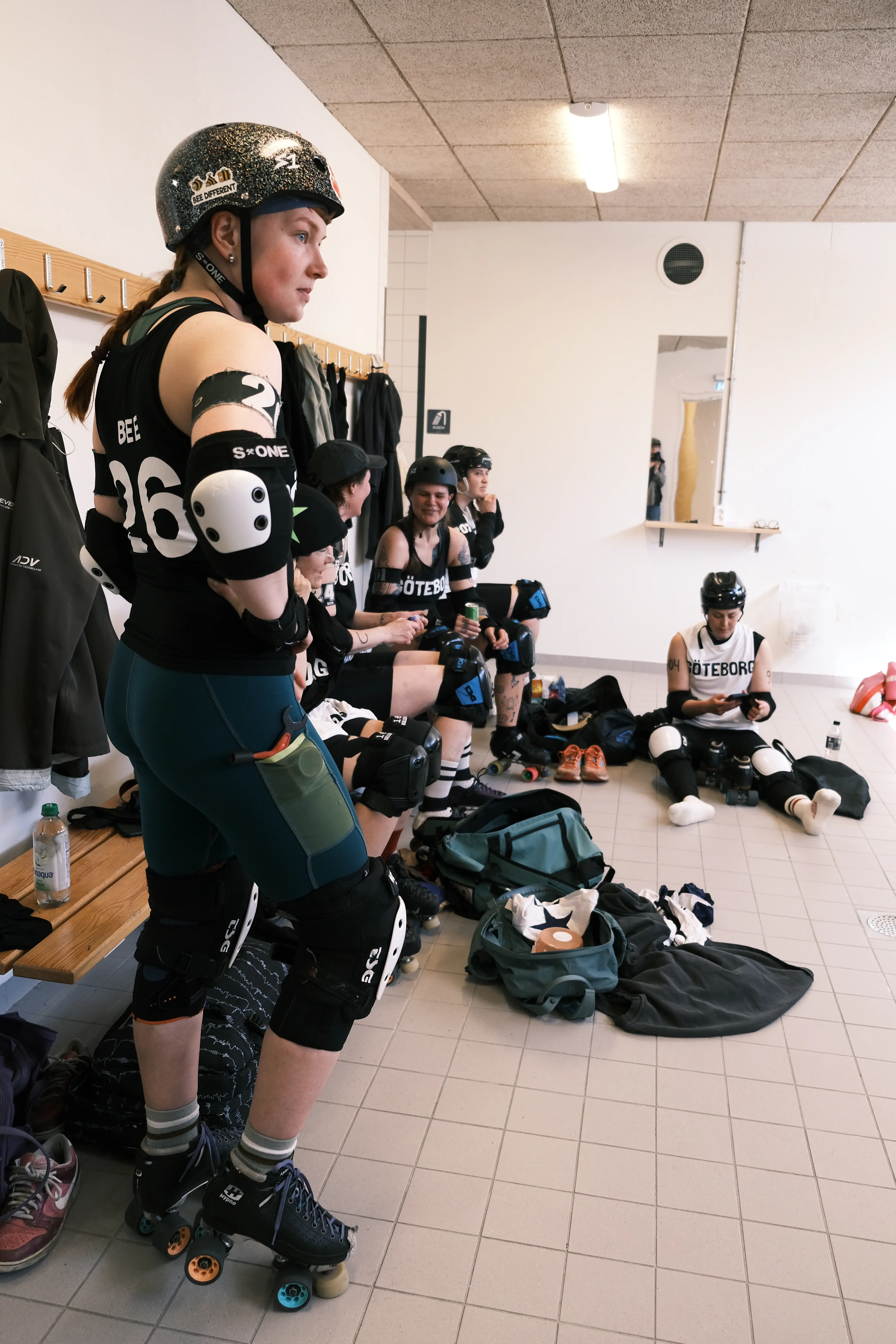 A roller derby player standing in full gear in a changing room.