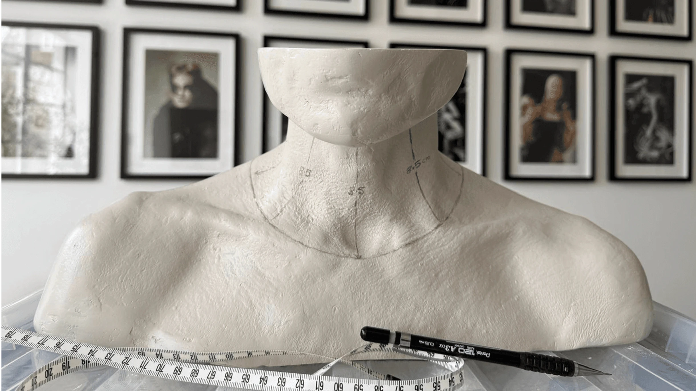 Hand-carved mannequin bust with neck measurements and design markings, displaying a fashion designer’s jewellery draping process in an artist studio.