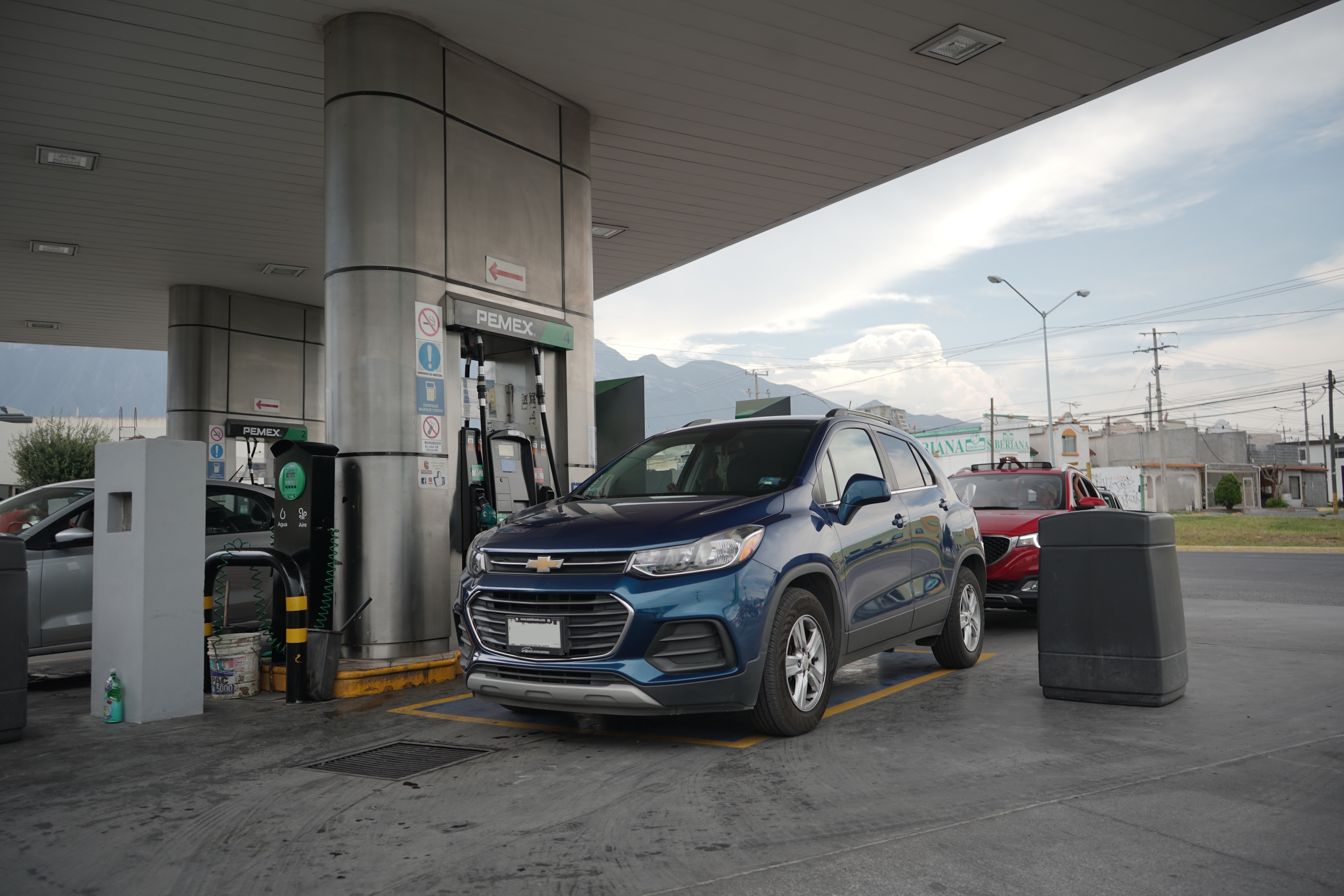 Spacious, luxurious living room with high ceilings, an elegant beige sectional sofa, warm ambient lighting, classical artwork, and rustic architectural elements, featuring an open layout with a view of a mezzanine level.