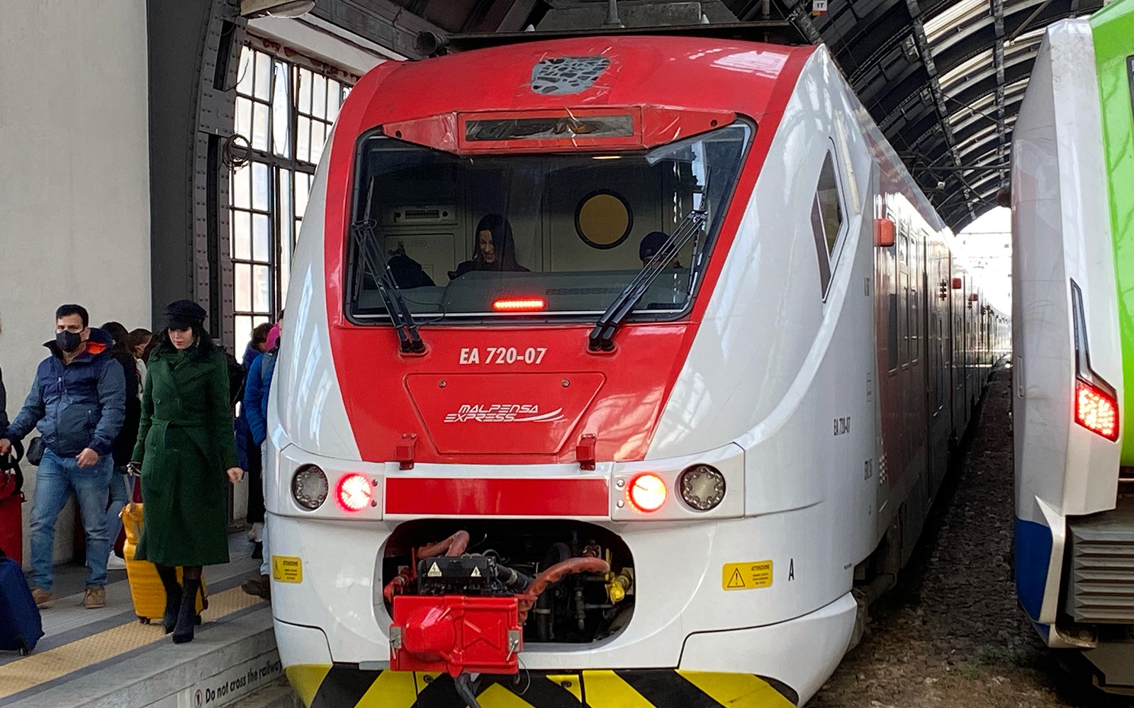 Malpensa Express lest á brautarpalli með farþegum, sem tengir flugvöllinn við aðallestarstöðina í Mílanó.
