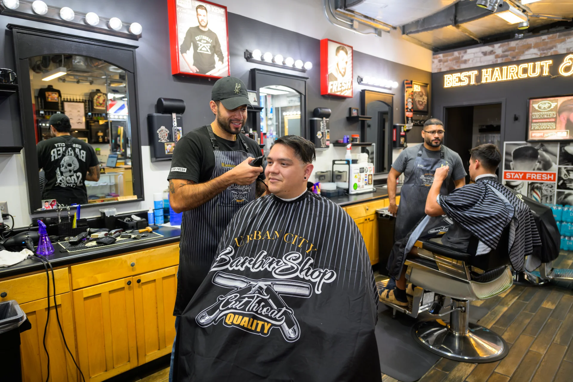 Barber trimming a client’s beard at Urban City Barber Shop, with a second barber working in the background