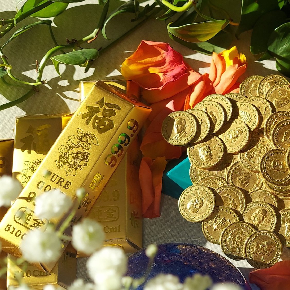 Gold coins, a red charm and a good fortune scroll arranged with a plant