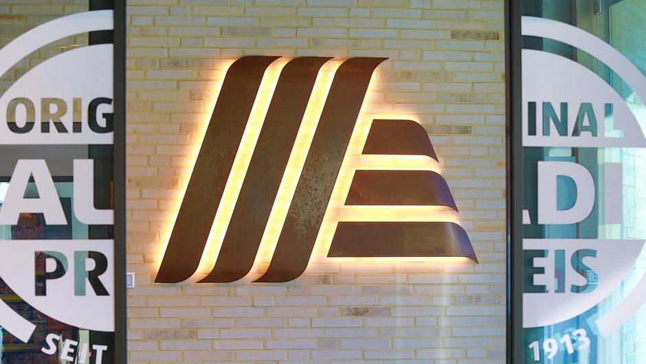 Das Aldi Süd-Logo als "Cortenstahl-Installation" sticht ins Auge. Der Händler möchte das neue Design der Filiale nicht als Prototyp verstehen. Stattdessen betont er die "Flexibilität", mit der er innenstädtische Räume begehen will.