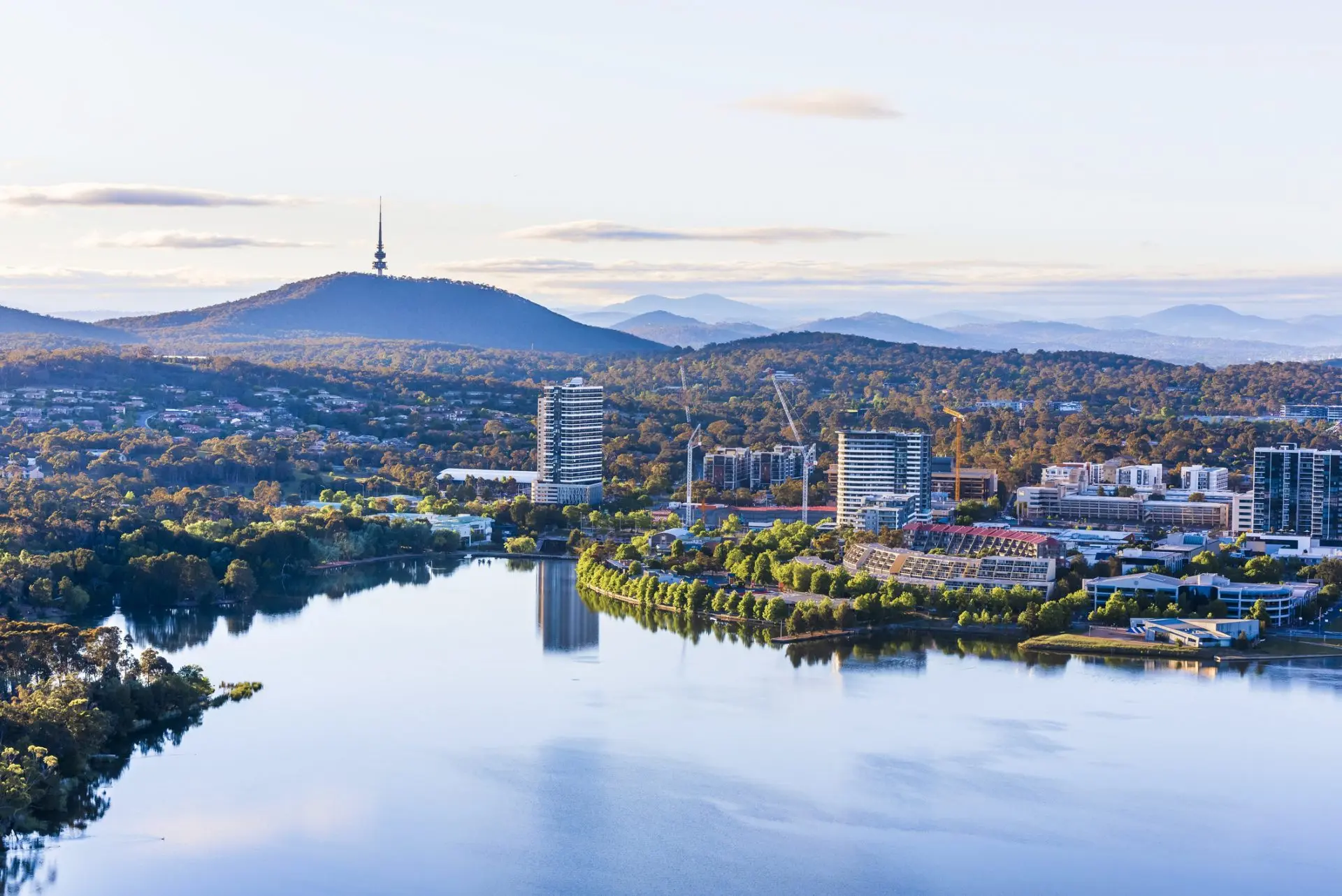 Lake and city skyline with distant tower and mountains
