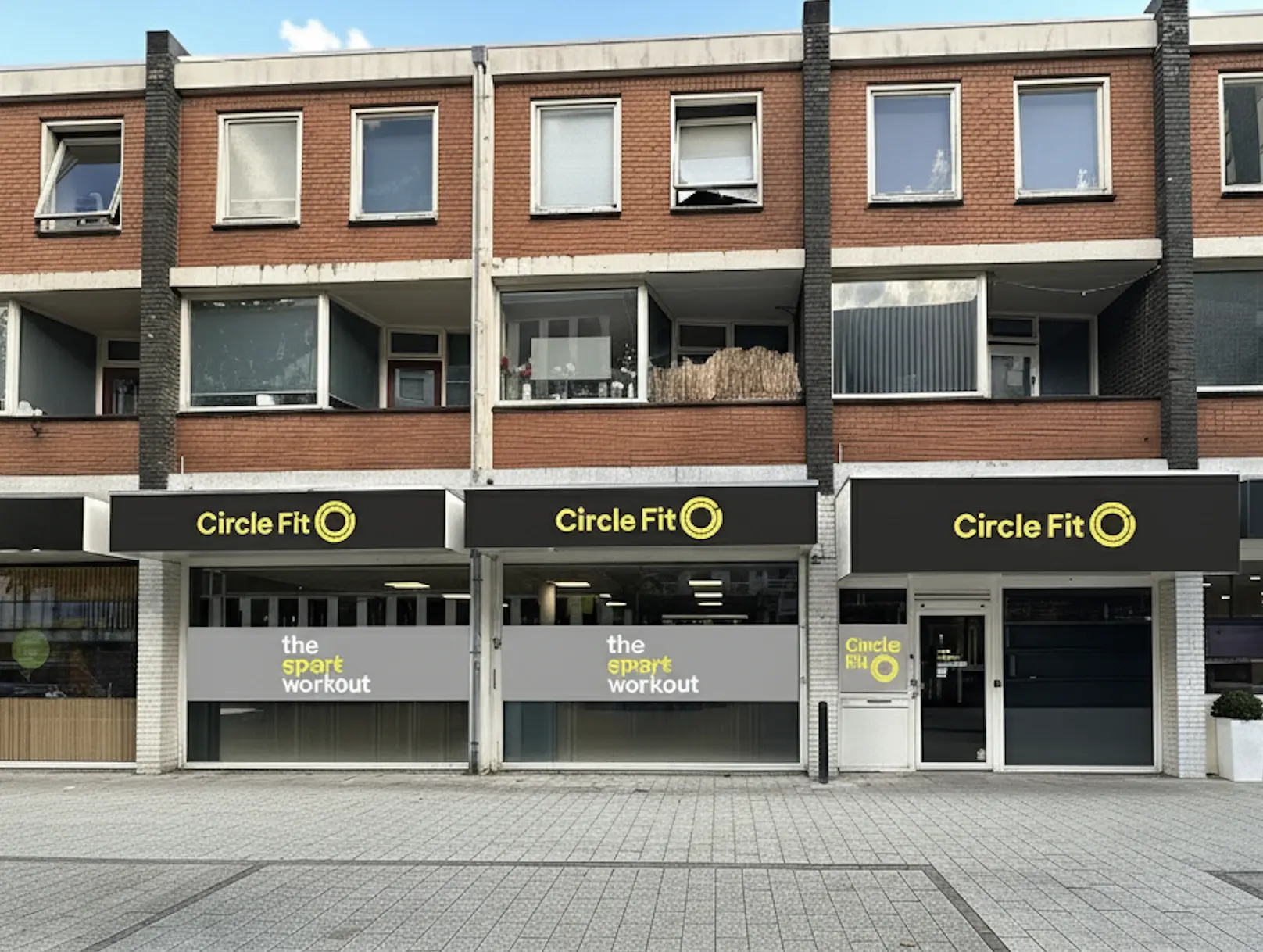 Een felgekleurd Circle Fit-hub exterieur met buitenzitplaatsen en een klein karretje op de stoep.