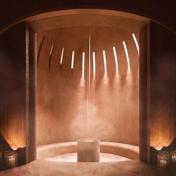 Warmly lit circular bathing room with a small central basin and curved architectural walls.