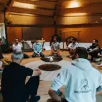 Mannen zitten in een kring in een houten zaal