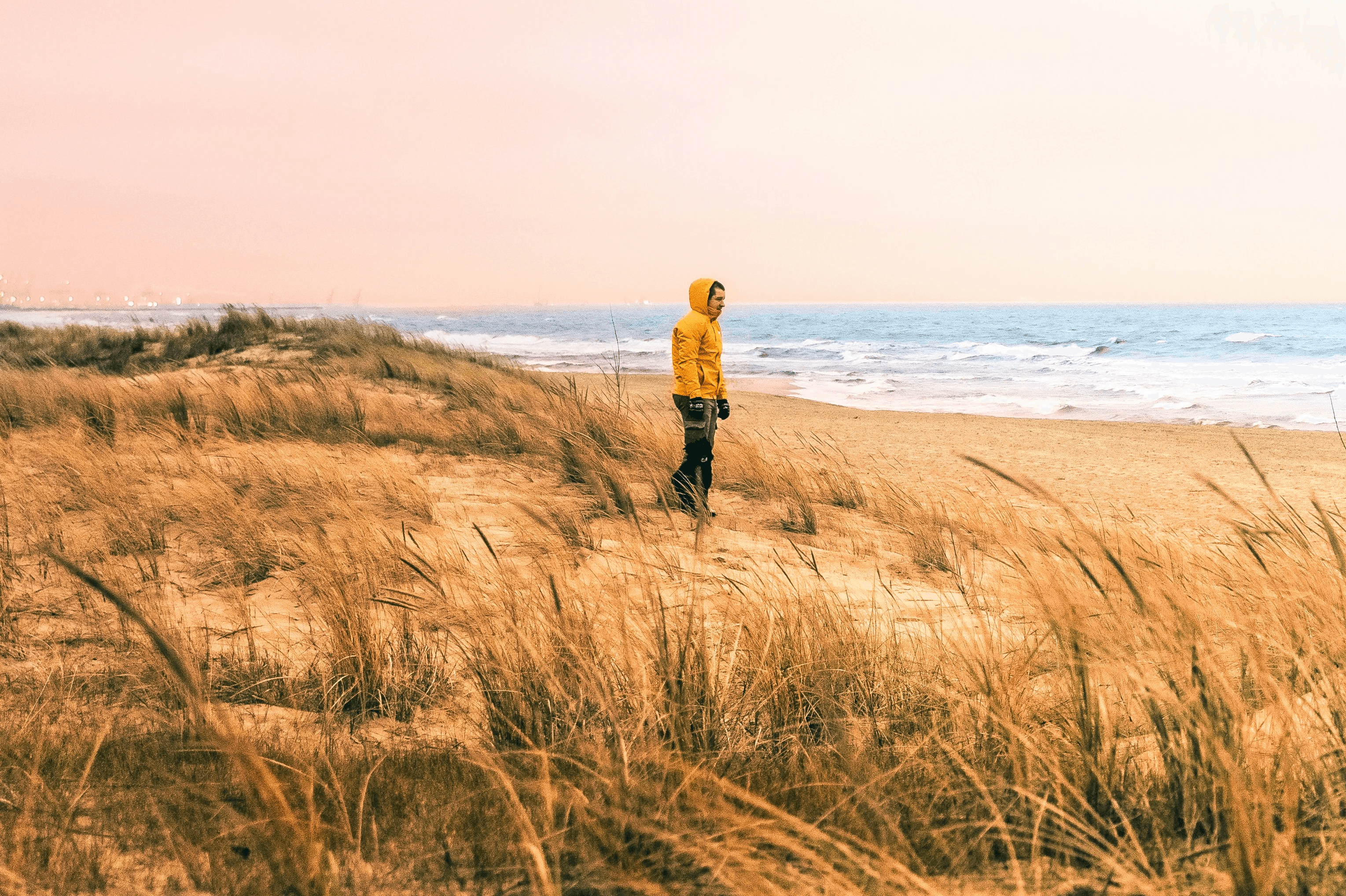 a person in a yellow jacket standing on a beach