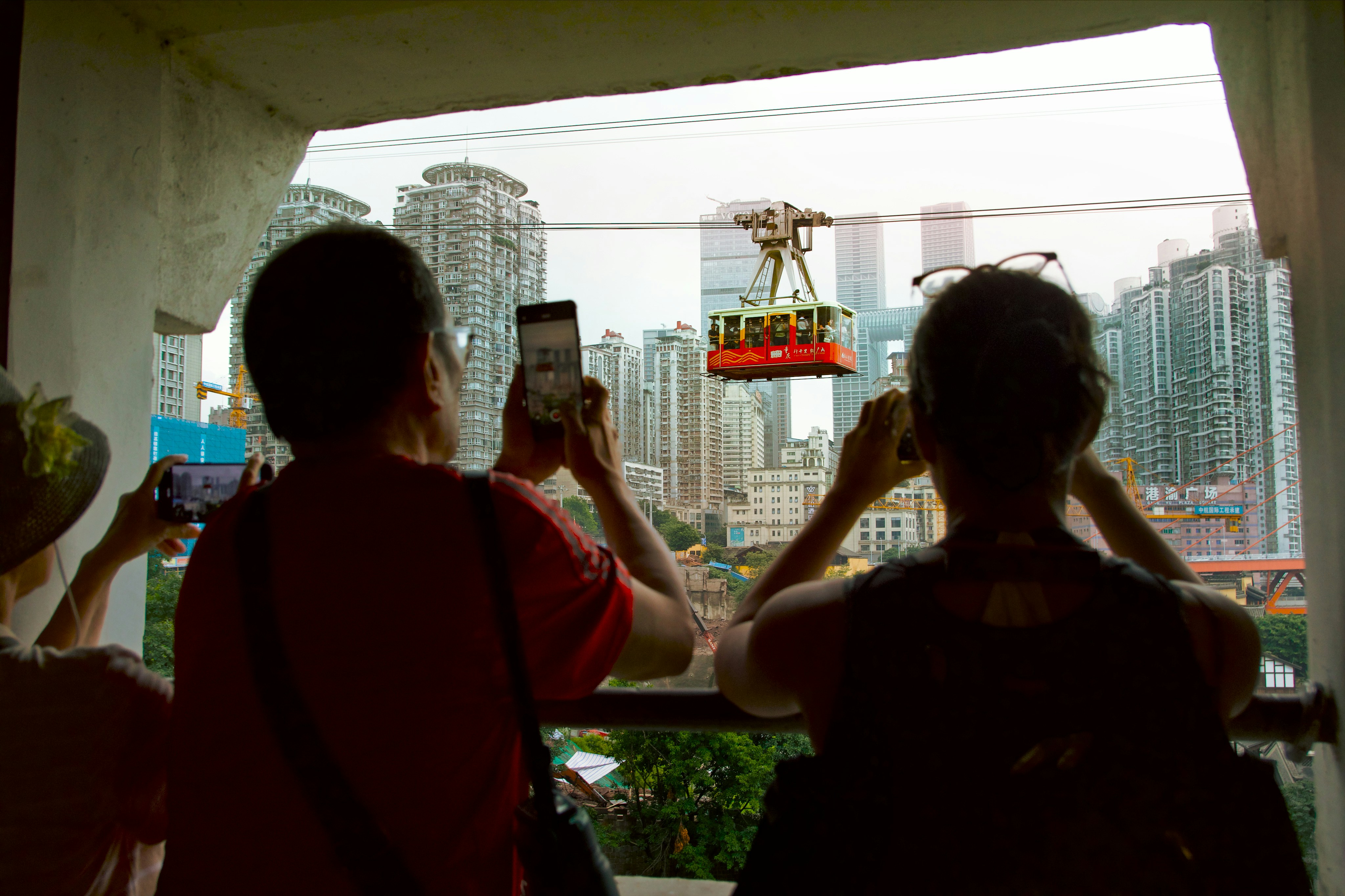 People taking photos of a cable car with city background.