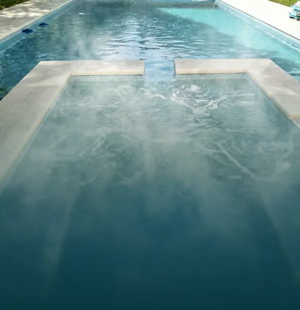 Vapor suave elevándose sobre la superficie de una pileta climatizada exterior, ideal para disfrutar del agua a temperatura perfecta todo el año.