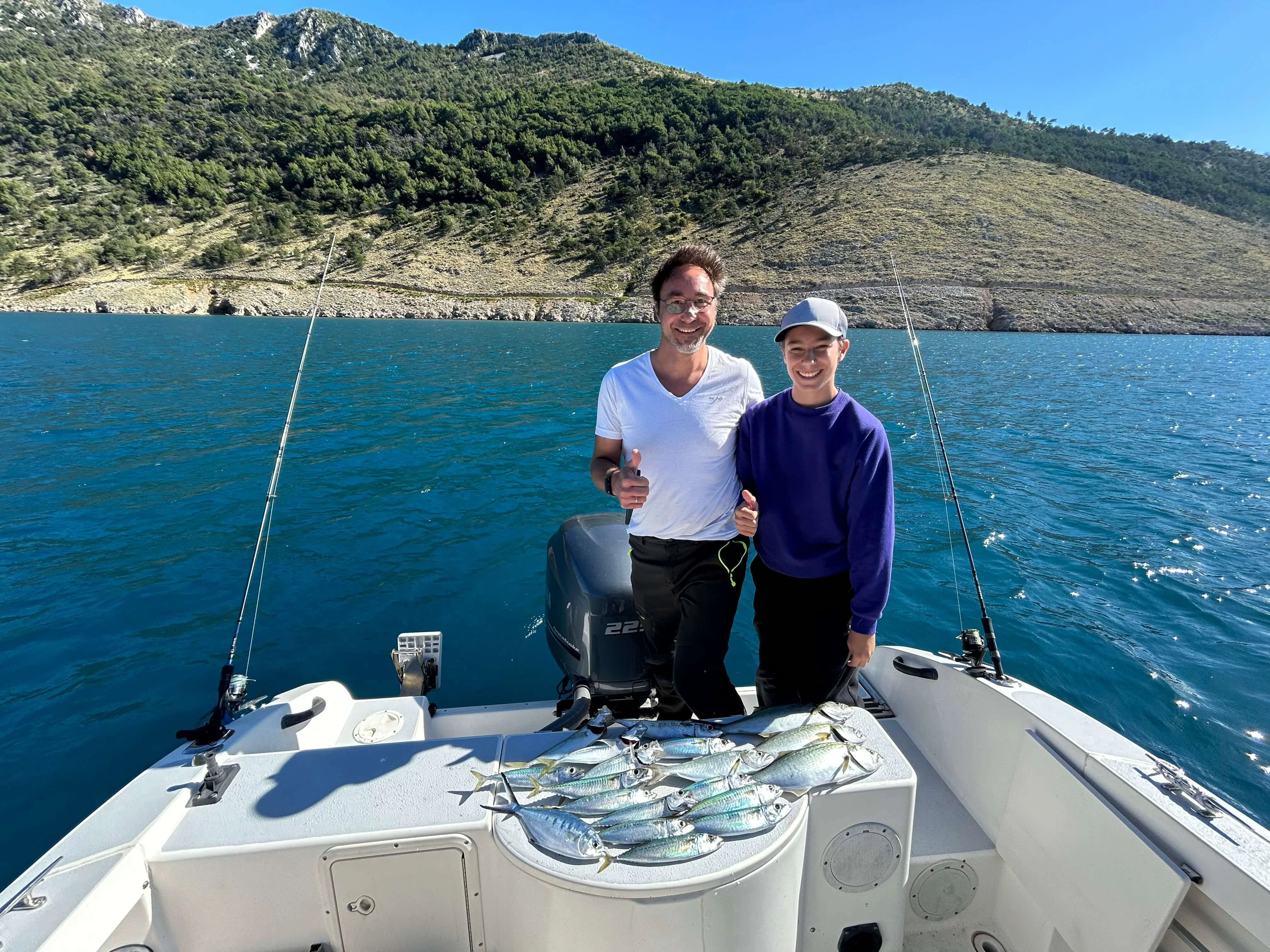 Father and son proudly displaying freshly caught fish during a family fishing trip on the Adriatic Sea.