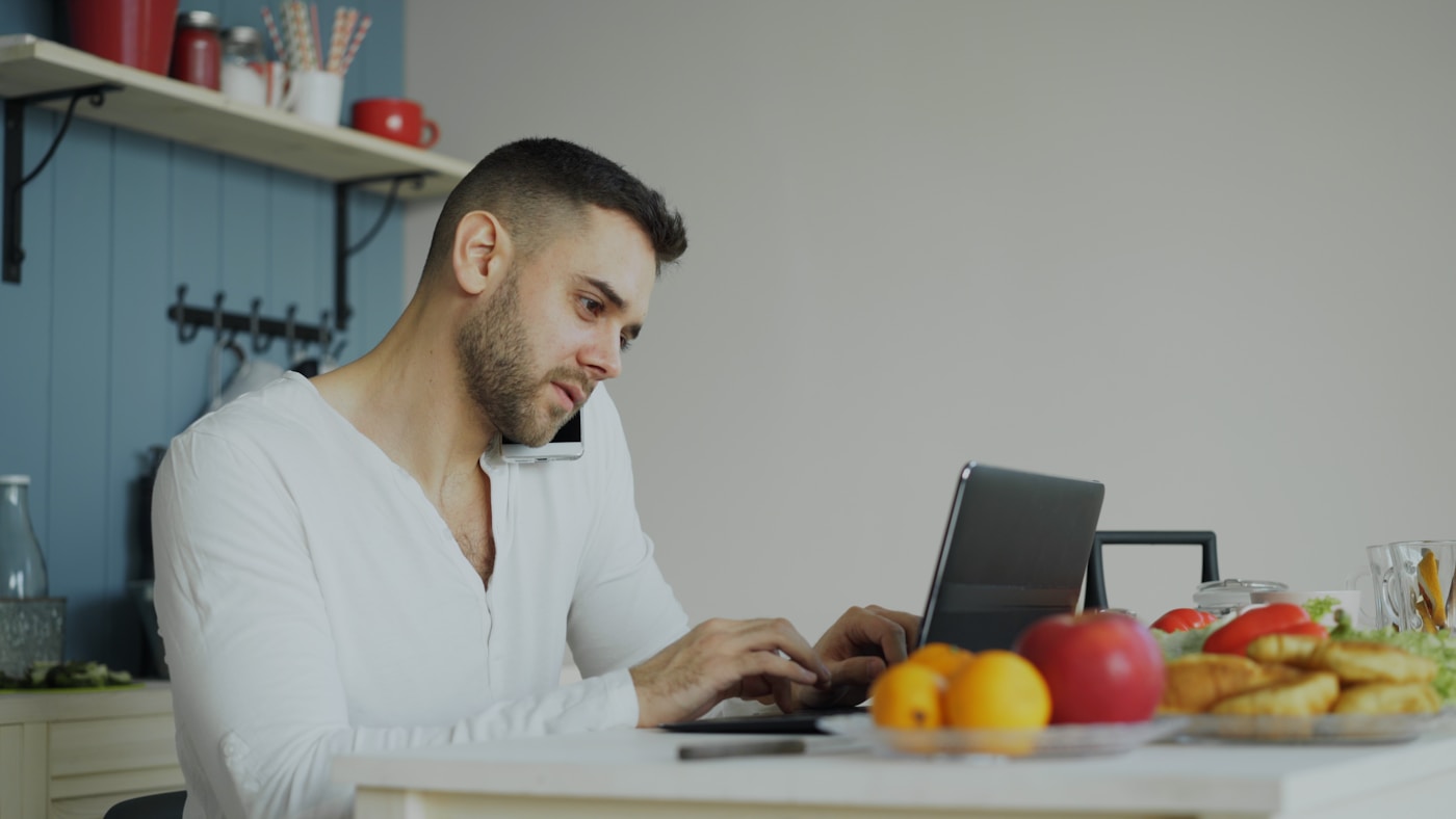 A parent joining a virtual nutrition visit on a laptop at the kitchen table with fresh food nearby