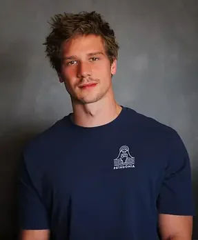 Jan Schmoltner im blauen Shirt mit Aufdruck vor grau meliertem Hintergrund