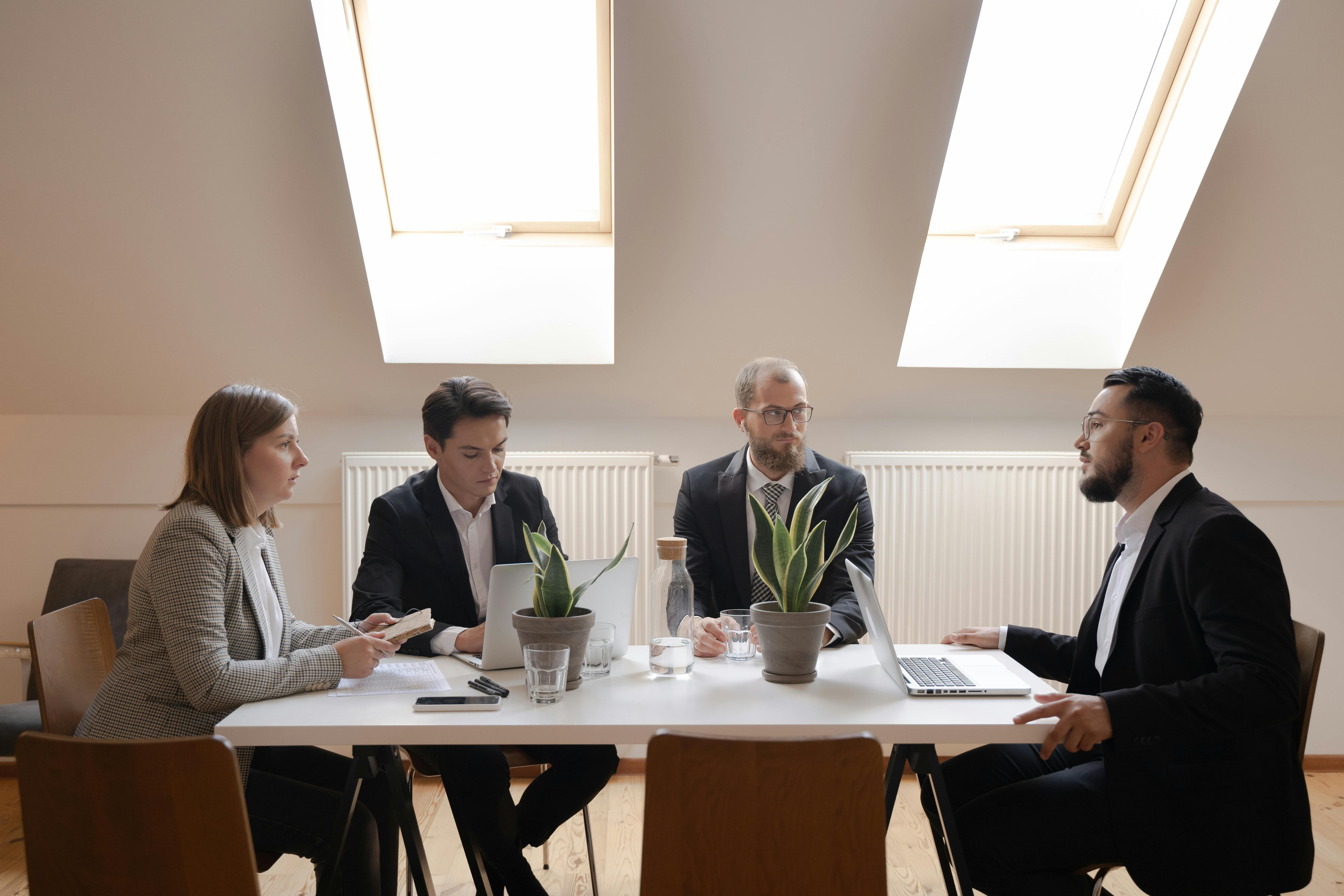 Four professionals in a business meeting in a modern office.
