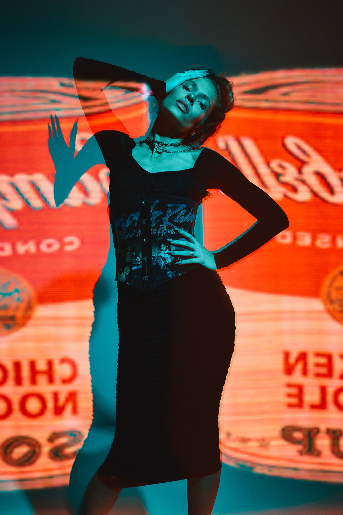 A model poses with one arm raised in front of a projected Campbell’s soup label at Revelator Studio, Shreveport’s top natural light studio for creative photography.