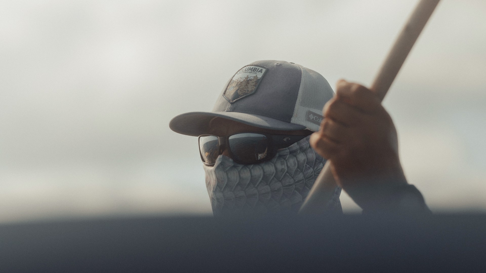 Tight crop portrait of Marlon Leslie with a push pole in his hand, wearing sunglasses and a cap