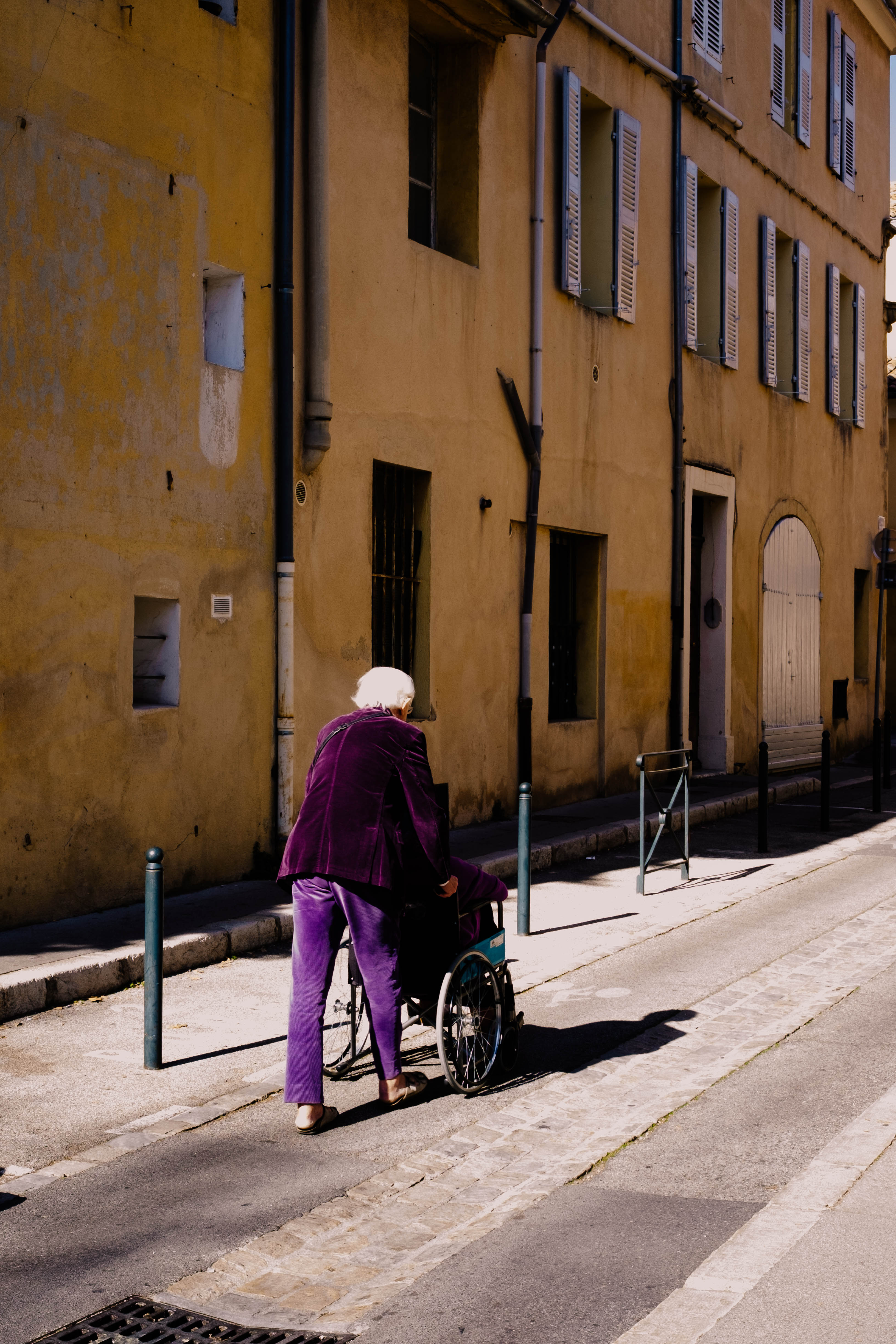A purple-dressed couple walks down a yellow street of Aix-en-Provence
