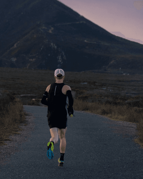 man running down road with mountain in background