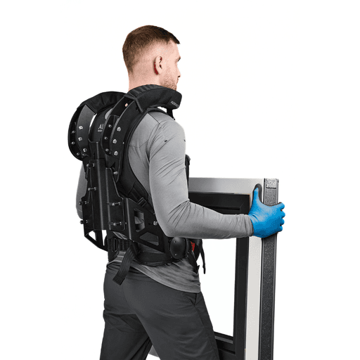 Man wearing a CarrySuit exoskeleton while carrying a heavy window, designed to reduce back pain and optimize handling in the construction and logistics sectors.